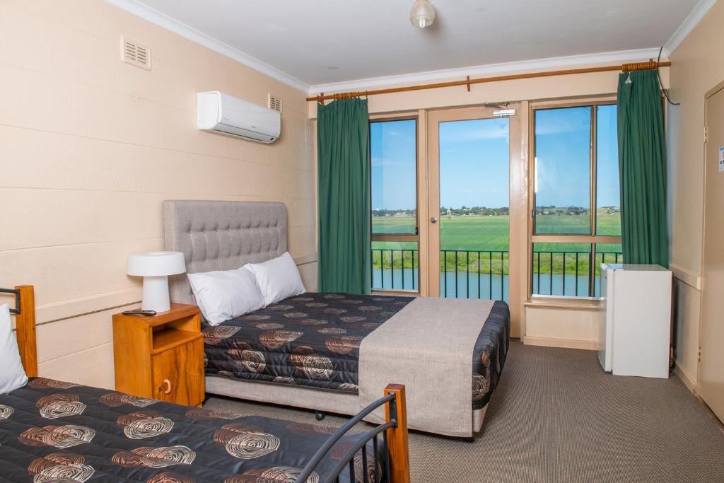 a hotel room with two beds and a balcony at Tailem Bend Riverside Hotel in Tailem Bend