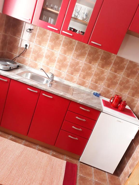 a kitchen with red cabinets and a sink at Apartmani RALE rooms in Sarajevo