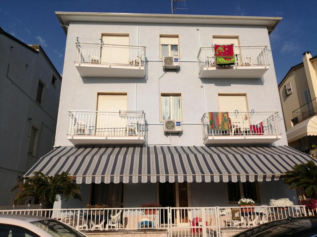 a tall white building with balconies and a awning at B&B GALLETTO in Porto San Giorgio