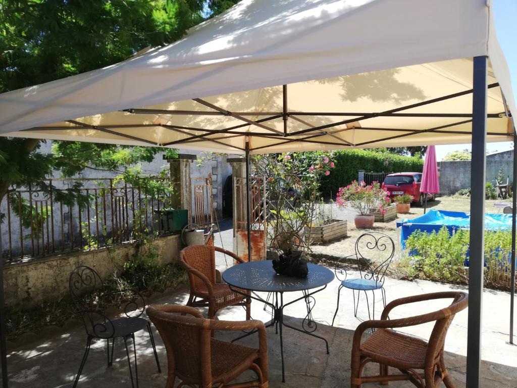 een patio met een tafel en stoelen onder een witte parasol bij terre et mer in Sainte-Ramée
