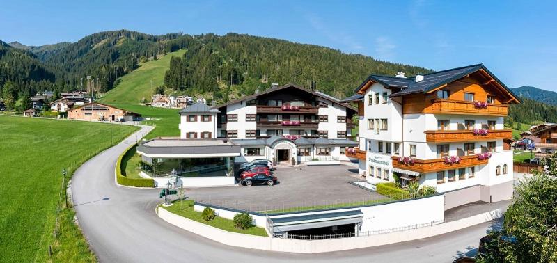 a large building with a parking lot next to a mountain at Hotel Waidmannsheil in Flachau
