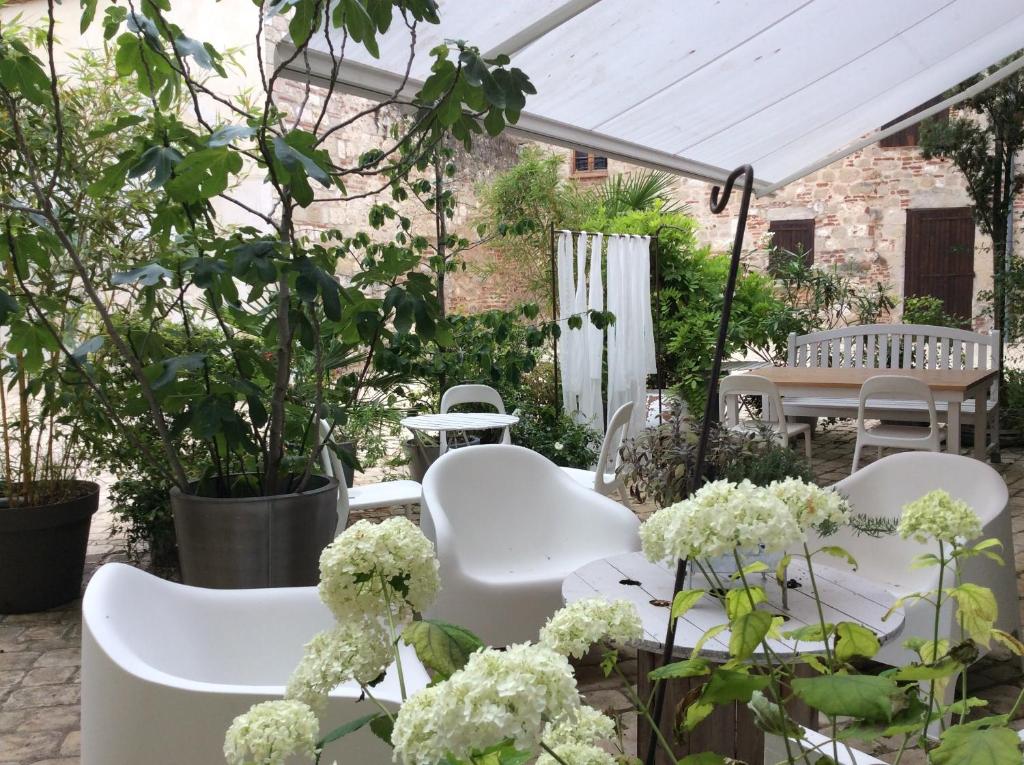 un groupe de chaises et de tables blanches dans un jardin dans l'établissement La maison sur la place, à Penne-dʼAgenais
