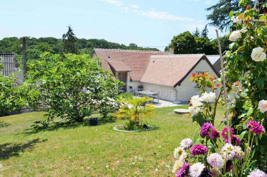 13 Rue du Perré Maison de vacances في La Membrolle-sur-Choisille: منزل مع حديقة مع الزهور في الفناء