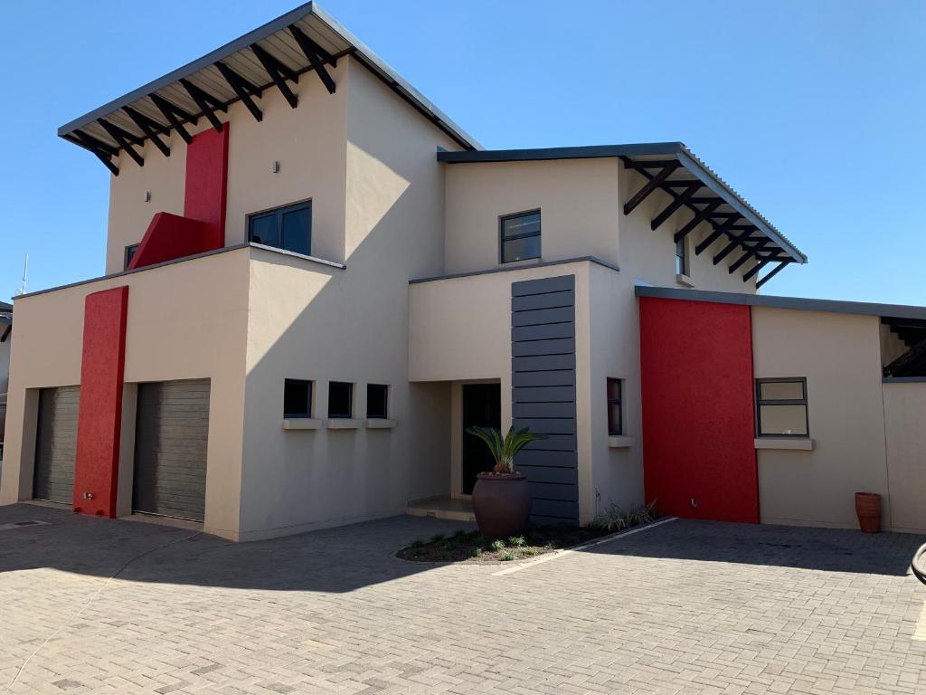 a white house with red doors and a potted plant at 66 Dorp Street Apartment in Polokwane