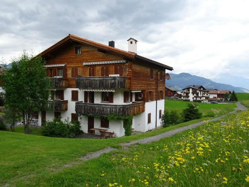 a wooden house on a hill with a green field at Gadahüs 4 Elvers Misanenga - Ferienwohnung mit Bad/WC, 54 m2 für max. 4 Personen in Obersaxen