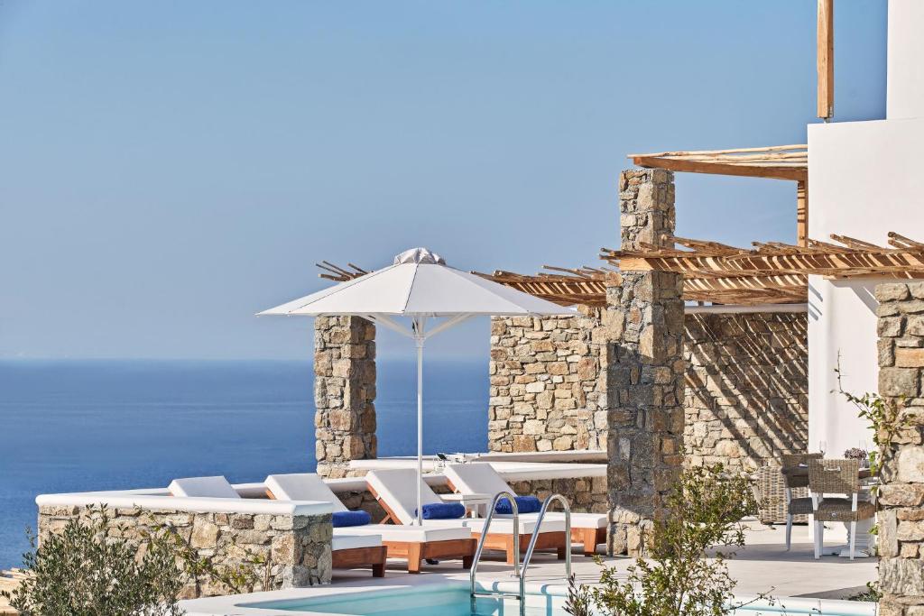 a patio with chairs and an umbrella and a pool at Katikies Villas Mykonos in Elia Beach