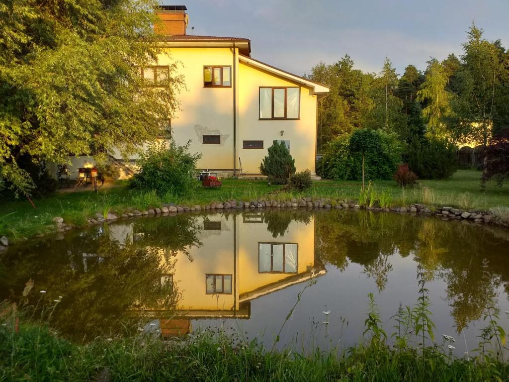 a house with a pond in front of it at Guest House Pechersky & Sons in Dreiliņi