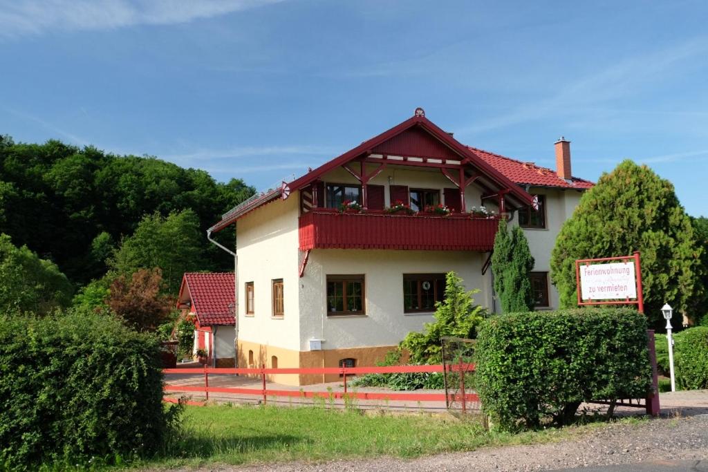 uma casa branca com um telhado vermelho em Ferienwohnung am Rennsteig em Wolfsburg-Unkeroda