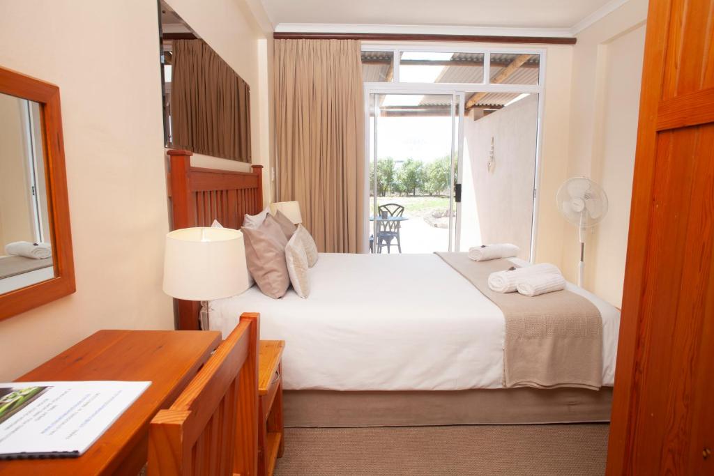 a bedroom with a bed and a desk and a window at Masada Guest House in Langebaan