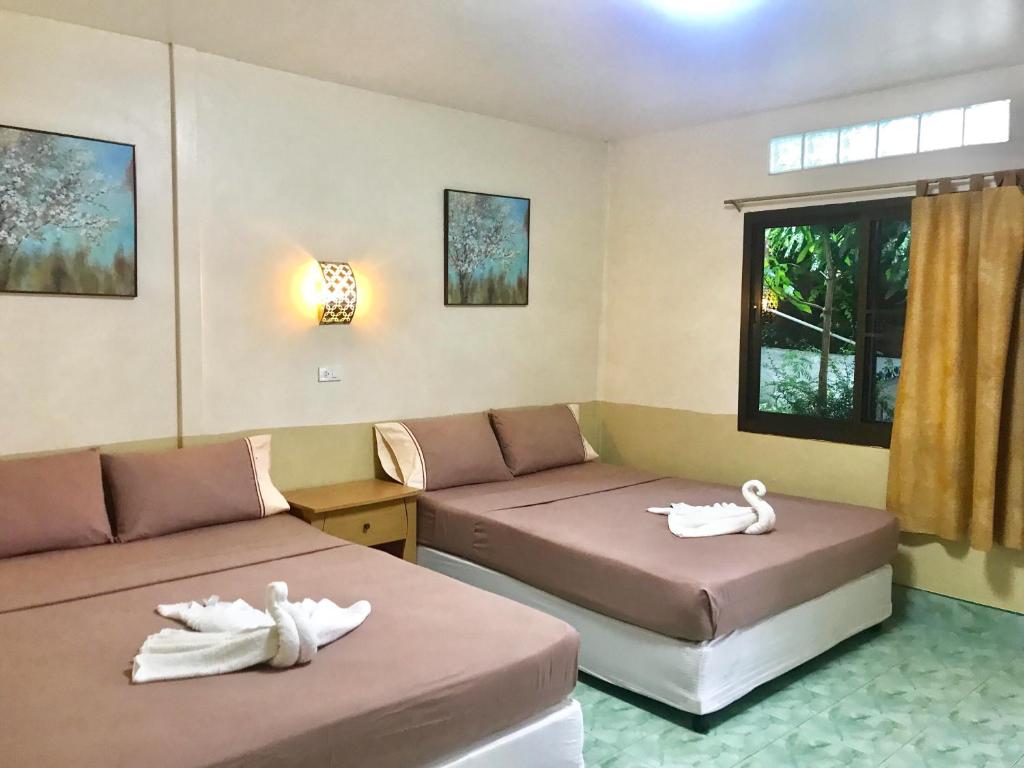 2 Betten in einem Zimmer mit Schwänen darauf in der Unterkunft Coco's Guest House in Ko Phi Phi