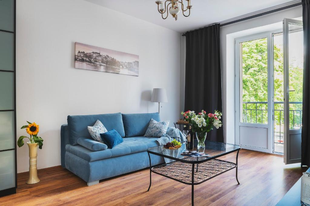 sala de estar con sofá azul y mesa de cristal en Sandomierska P&O Apartments, en Varsovia