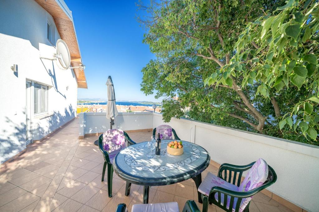 a table and chairs on a patio with a tree at Apartmani Patača in Vodice
