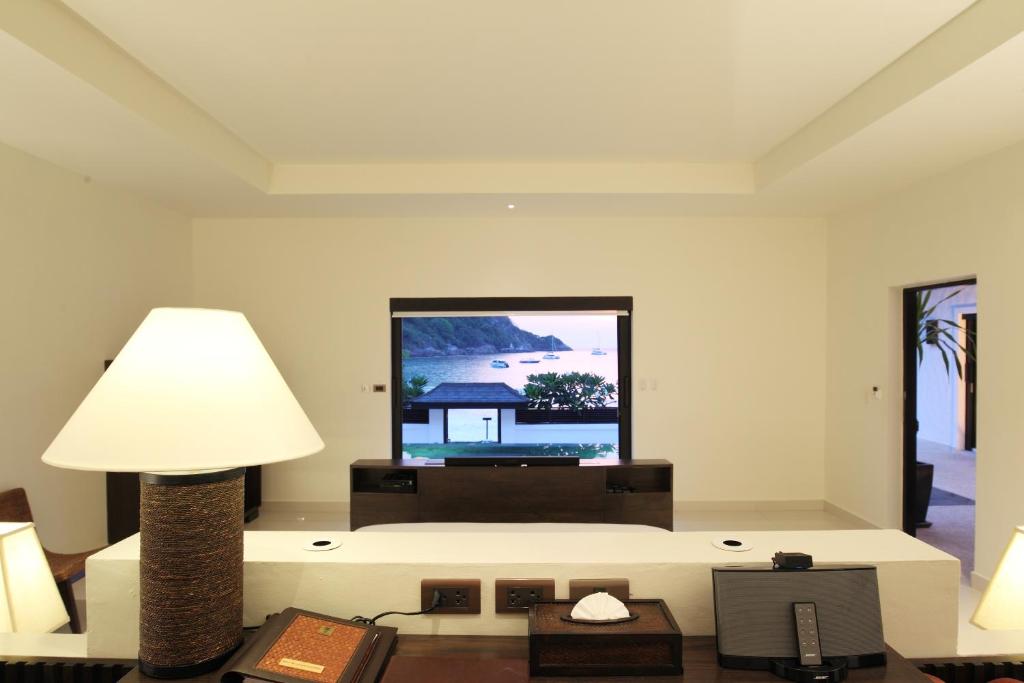 a living room with a tv and a lamp at The Racha in Ko Racha Yai 