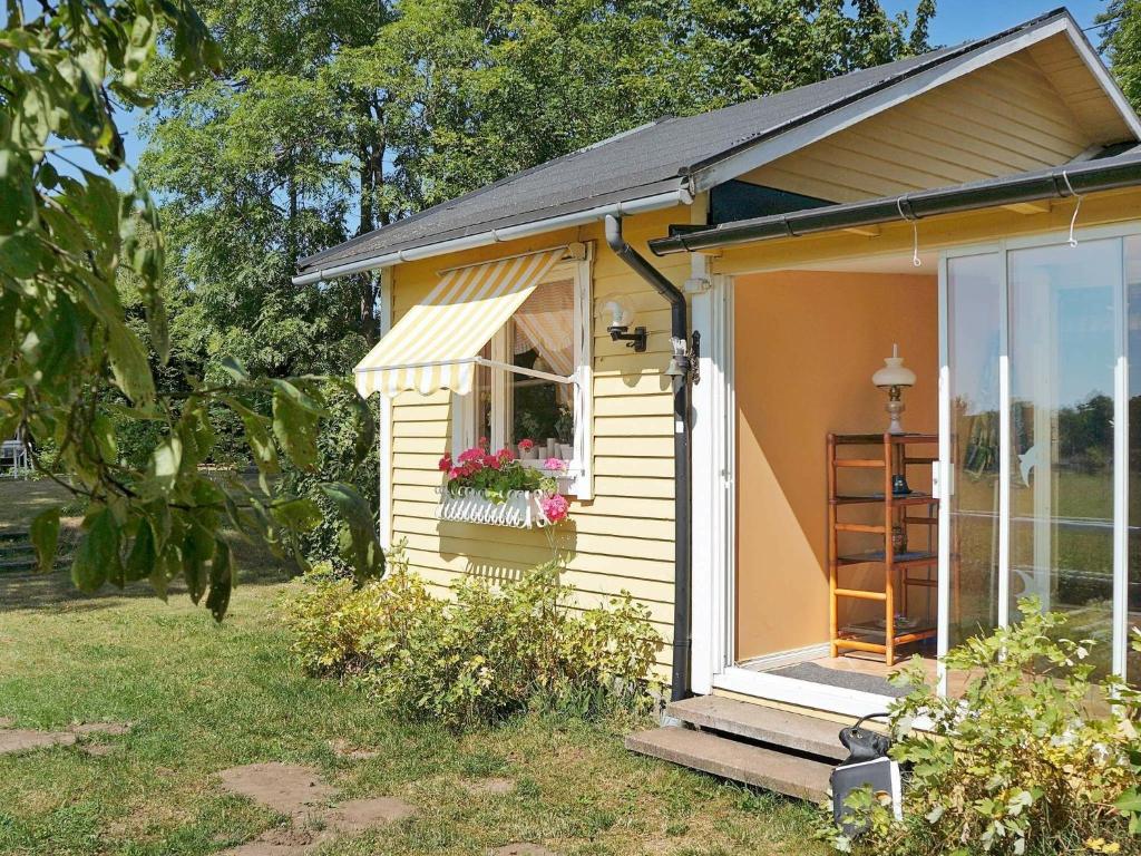 ein kleines gelbes Haus mit einem Fenster mit Blumen darin in der Unterkunft One-Bedroom Holiday home in Hästveda in Lur