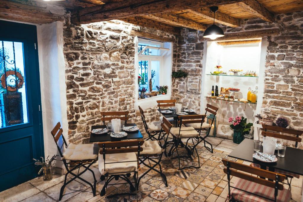 un restaurante con mesas y sillas y una pared de piedra en Guesthouse Centrum B&B, en Izola