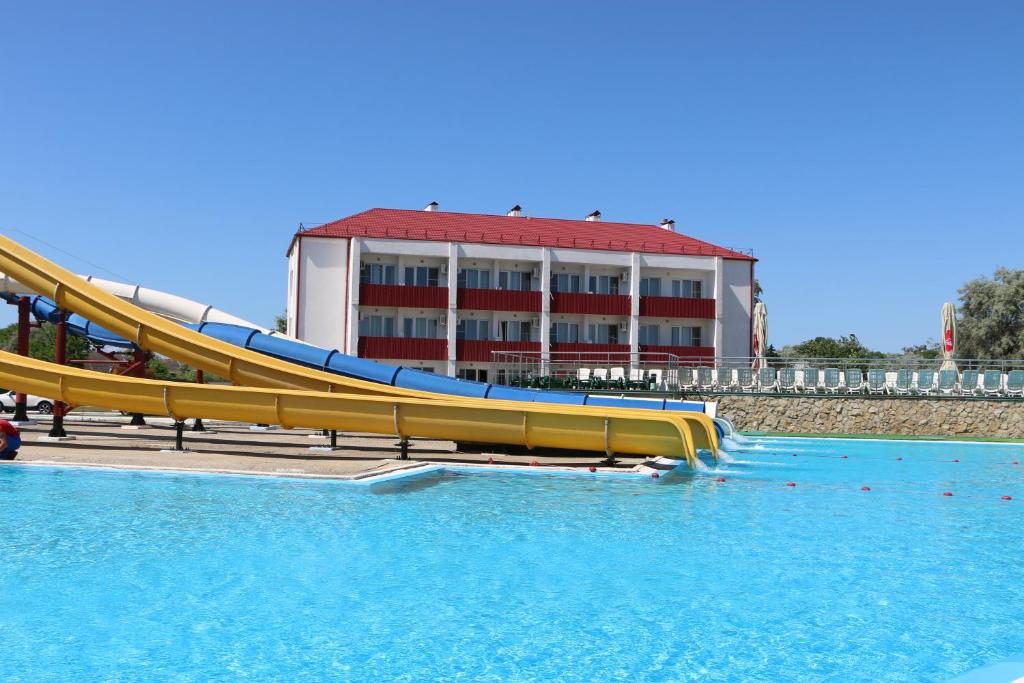 a slide in a pool of water in front of a building at Mini-Hotel Morskoi rif in Golubitskaya