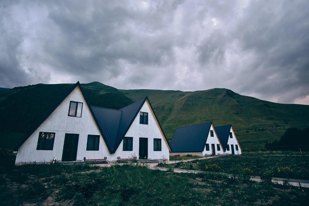 szereg białych domów z górami w tle w obiekcie Twins Achkhoti w mieście Stepancminda