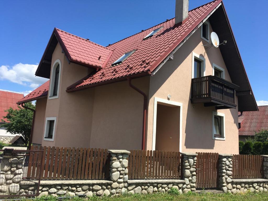 una casa con una valla y un techo rojo en Privat Patty, en Stará Lesná