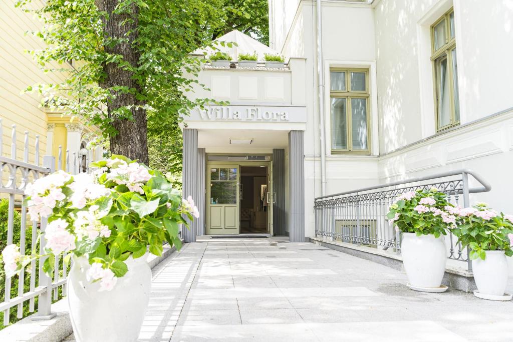 Hotel Willa Flora في شتتين: مبنى أبيض به ورود في مزهريات بيضاء على الرصيف