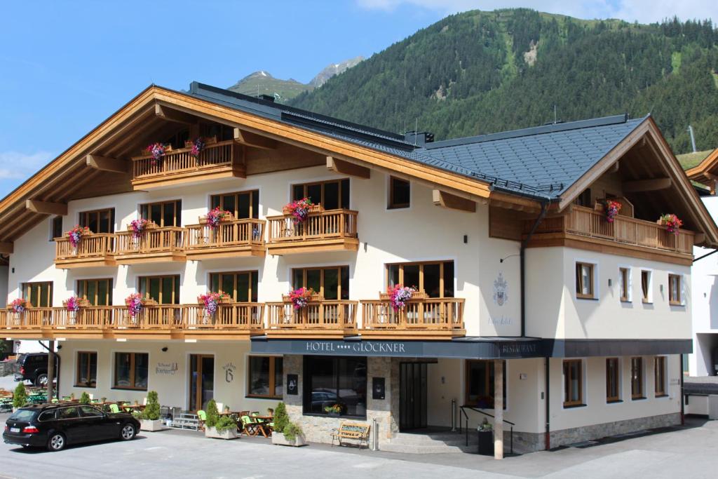 a large white building with a balcony with flowers on it at Hotel Glöckner und Hotel Residenz Glöckner in Ischgl