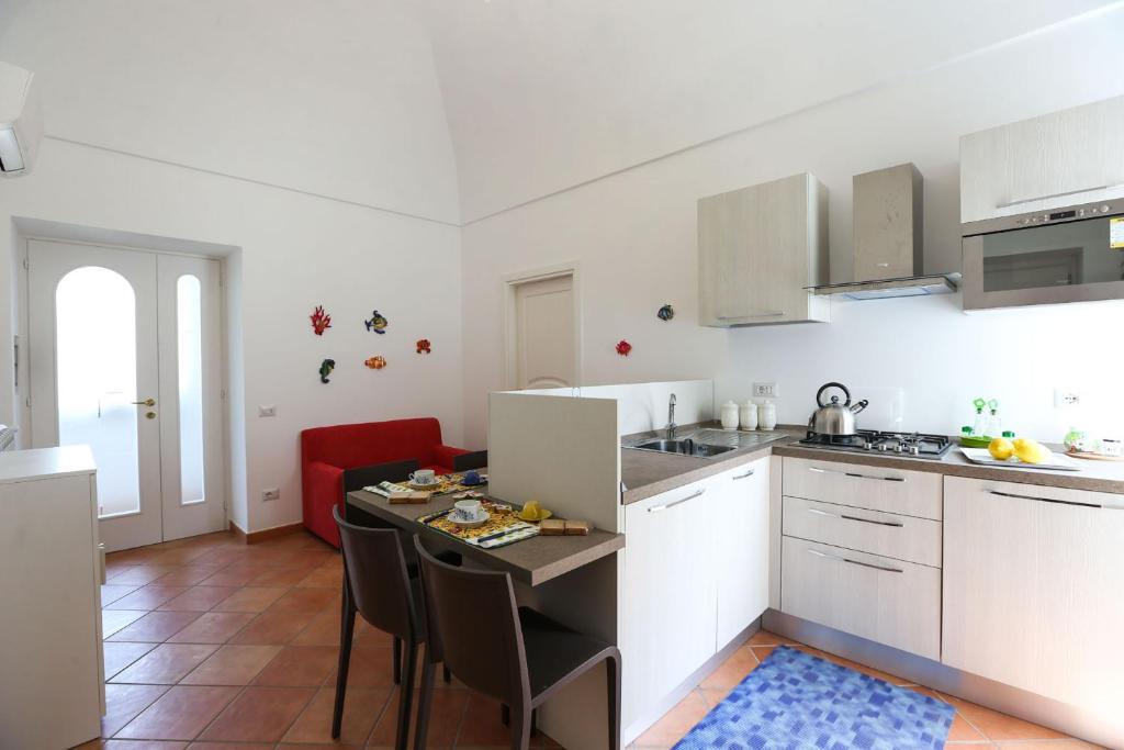 a kitchen with white cabinets and a table with chairs at Casa Ponticeto in Ravello