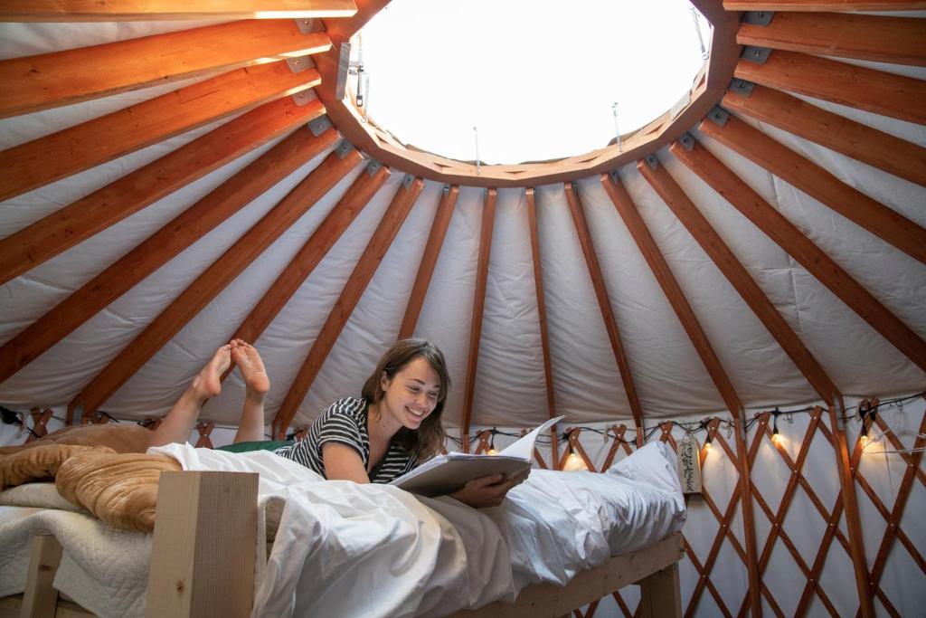 a woman laying on a bed in a yurt at The Yurts at Margo's Garden, Kiroro in Akaigawa