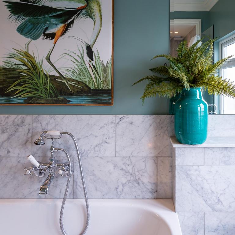 a bathroom with a bath tub with a bird painting on the wall at Roslin Beach Hotel in Southend-on-Sea