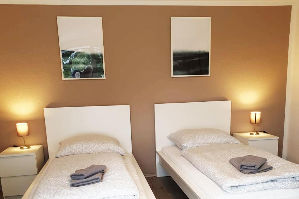 two beds in a room with two pictures on the wall at Moderne und sehr zentral gelegene Apartments in Neuss