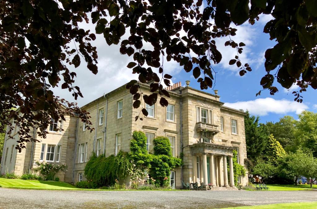 a large stone building with trees in front of it at Netherdale House & The Coach House in Turriff