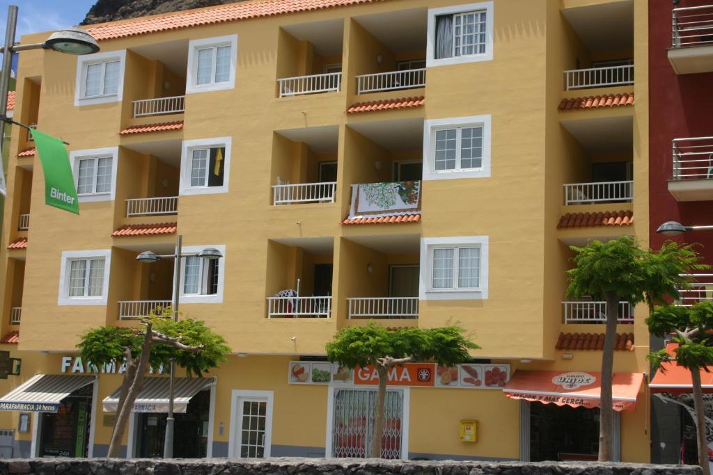 Un edificio amarillo con palmeras delante. en Apartamento Luz y Mar, en Tazacorte