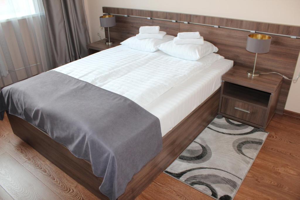 een slaapkamer met een groot bed met witte lakens en kussens bij Гостиница ОКА in Kaloega