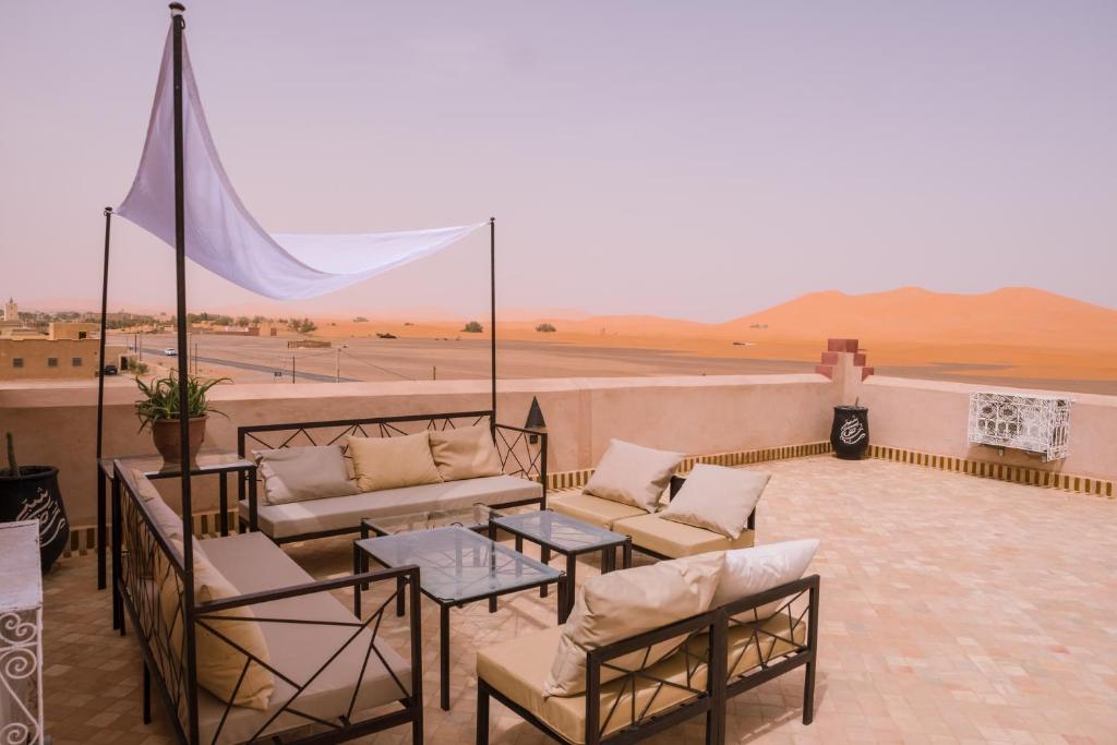 a balcony with a couch and chairs and a view of a desert at Riad Chebbi in Merzouga