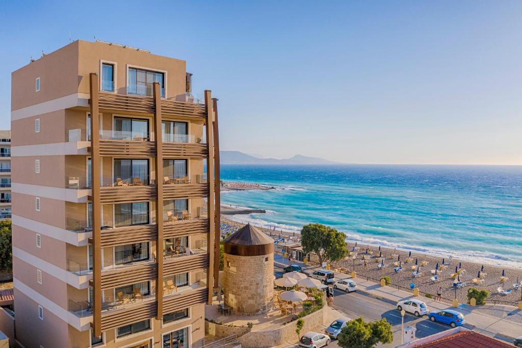 um edifício ao lado de uma praia com o oceano em Bellevue On The Beach Suites in Ilha de Rhodes