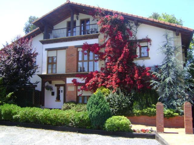 Una gran casa blanca con flores rojas. en Apartamentos Dos Robles, en Somo