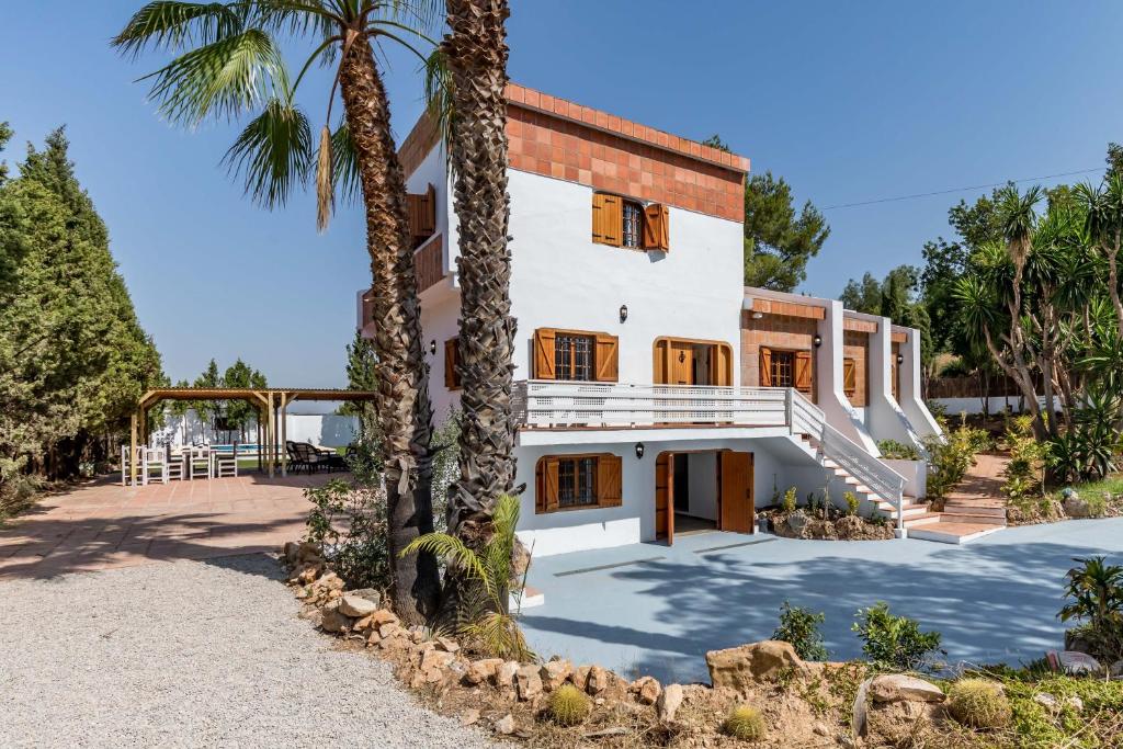 an exterior view of a house with palm trees at La Colina in Puebla de Vallbona