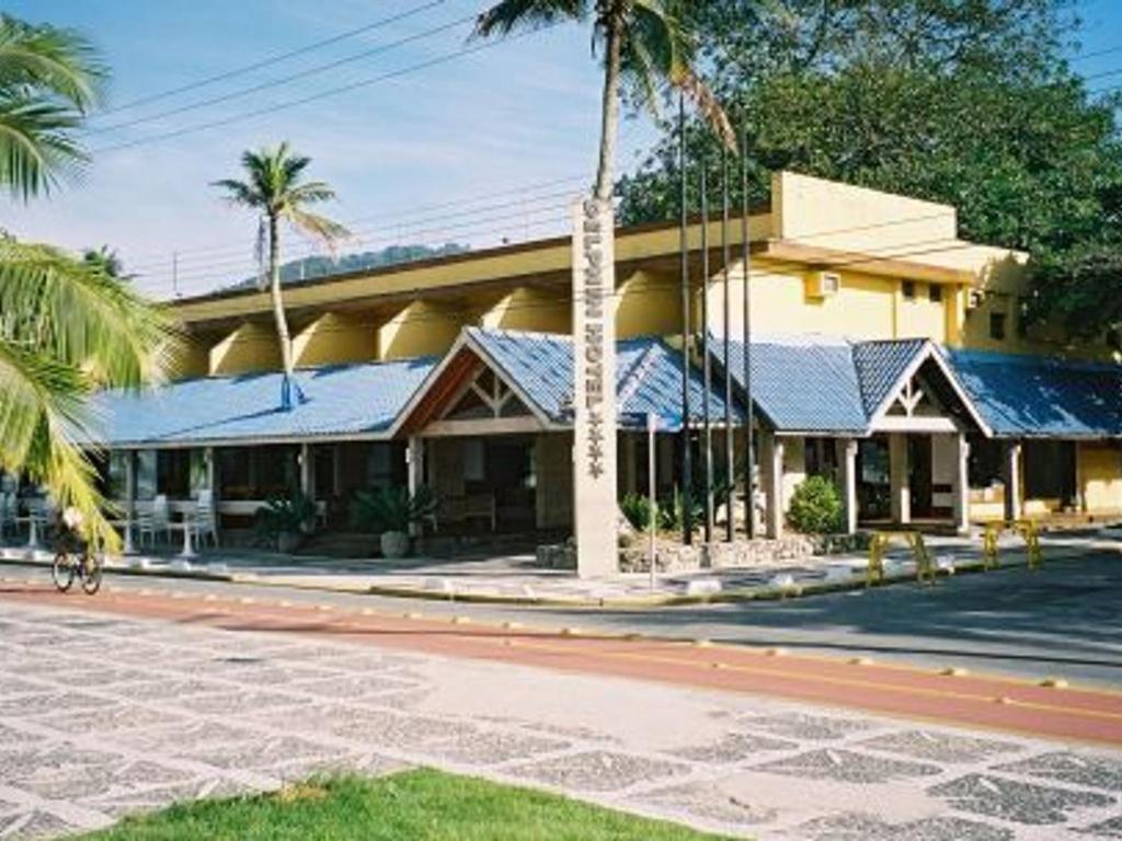 een gebouw met palmbomen voor een straat bij Flats Enseada Delphin in Guarujá