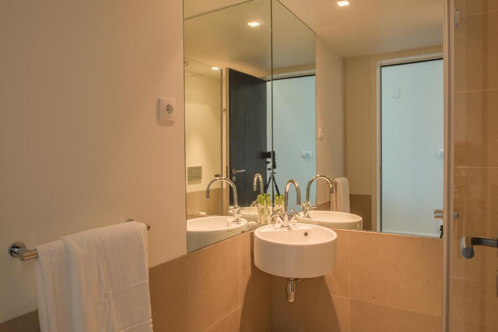 a bathroom with two sinks and a large mirror at Troia Residence by The Editory - Apartamentos Marina in Troia