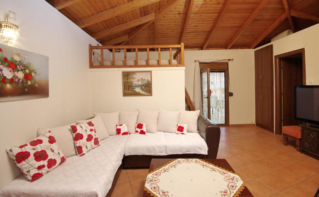 a living room with a white couch and a tv at NEFELI VILLA in Patitiri