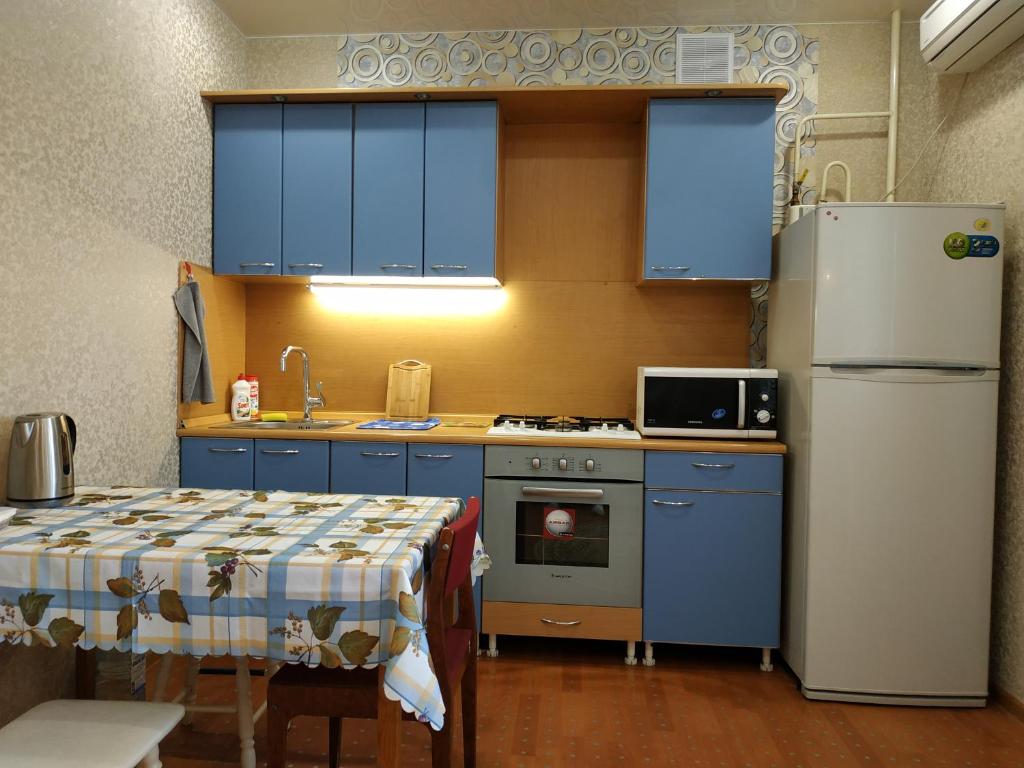 a kitchen with blue cabinets and a table and a refrigerator at Большая квартира с кондиционером на пр Ленина in Vladimir