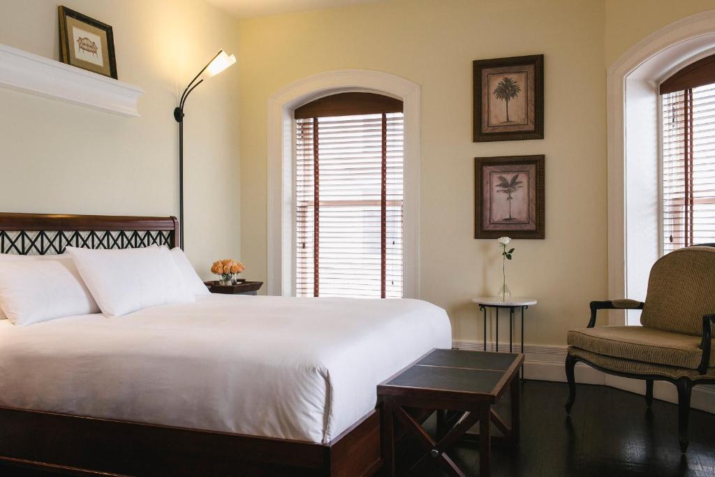 a bedroom with a large white bed and a chair at Hotel Place D'Armes in Montréal