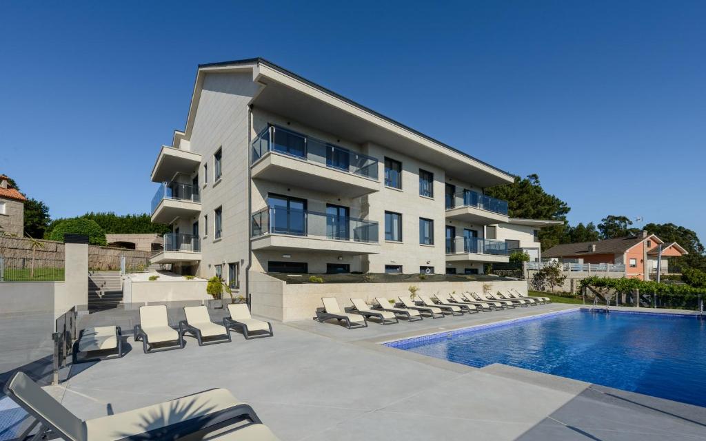 un edificio de apartamentos con piscina y tumbonas en Apartamentos Onzamar, en Sanxenxo