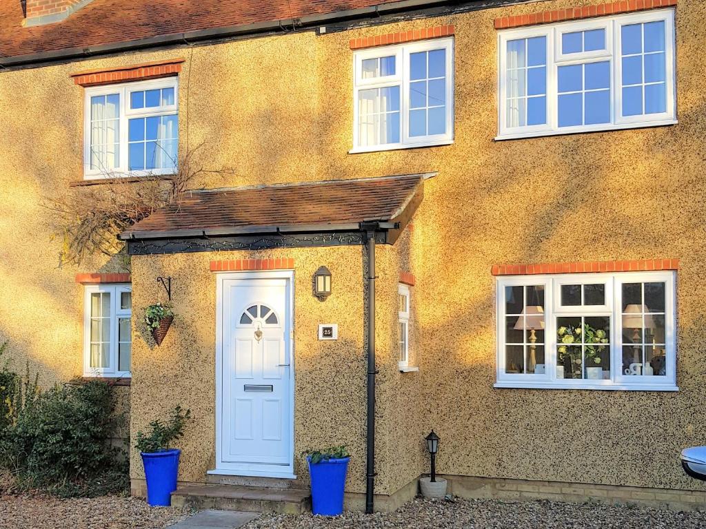 een huis met een witte deur en twee ramen bij Wisteria Haze in Cranfield