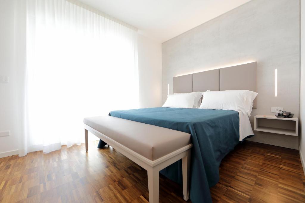 1 dormitorio con cama y banco. en Hotel Simi Lan, en Lignano Sabbiadoro
