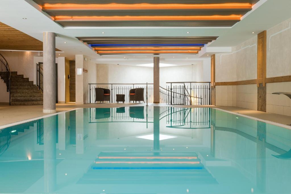 a swimming pool with blue water in a building at Hotel Lärchenhof in Solda