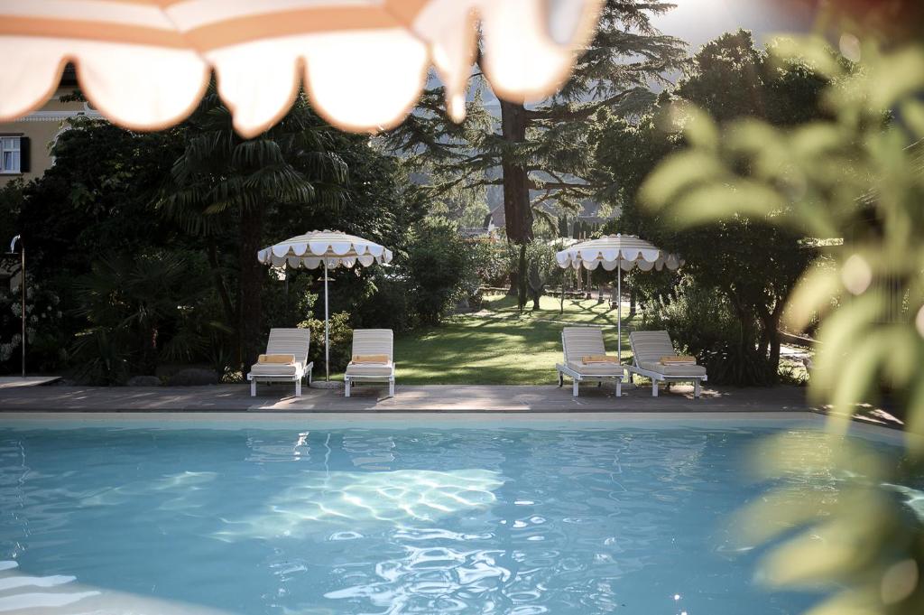 a group of chairs and umbrellas next to a swimming pool at Villa Arnica in Lana