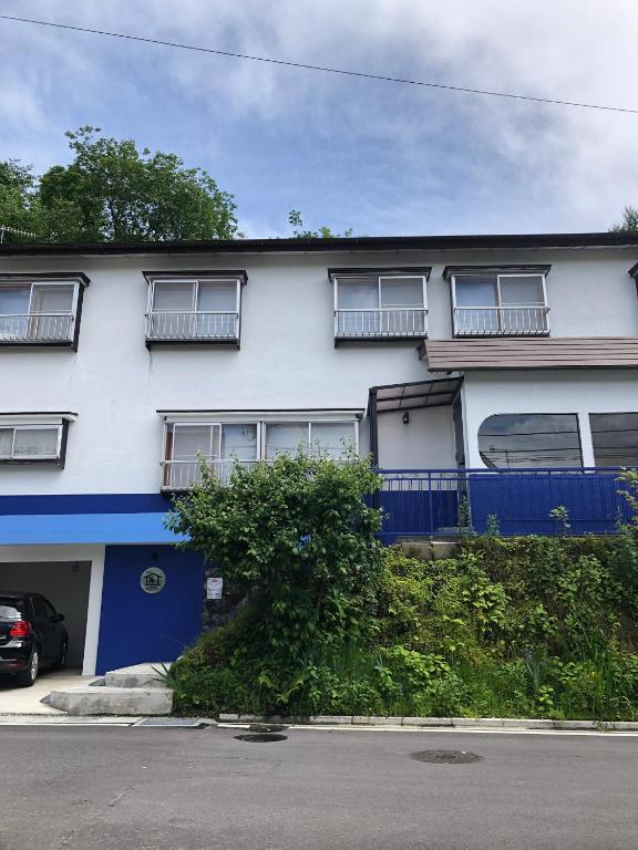 a white and blue building with a tree in front of it at Oyado Zen in Kusatsu