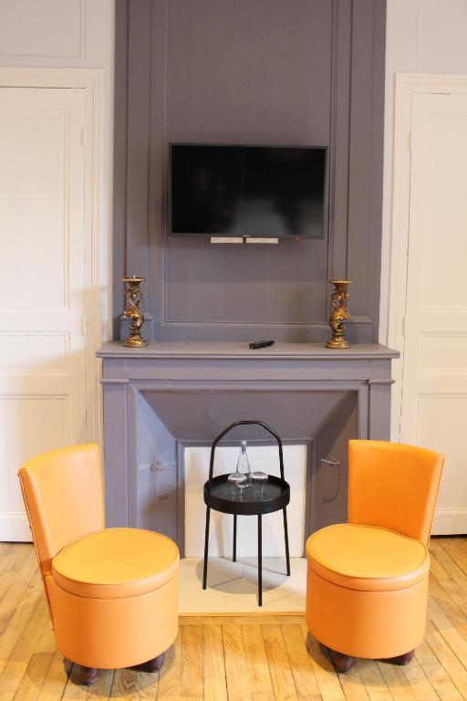 salon z 2 krzesłami i kominkiem w obiekcie Hôtel Les Empreintes w mieście Saint-Évarzec