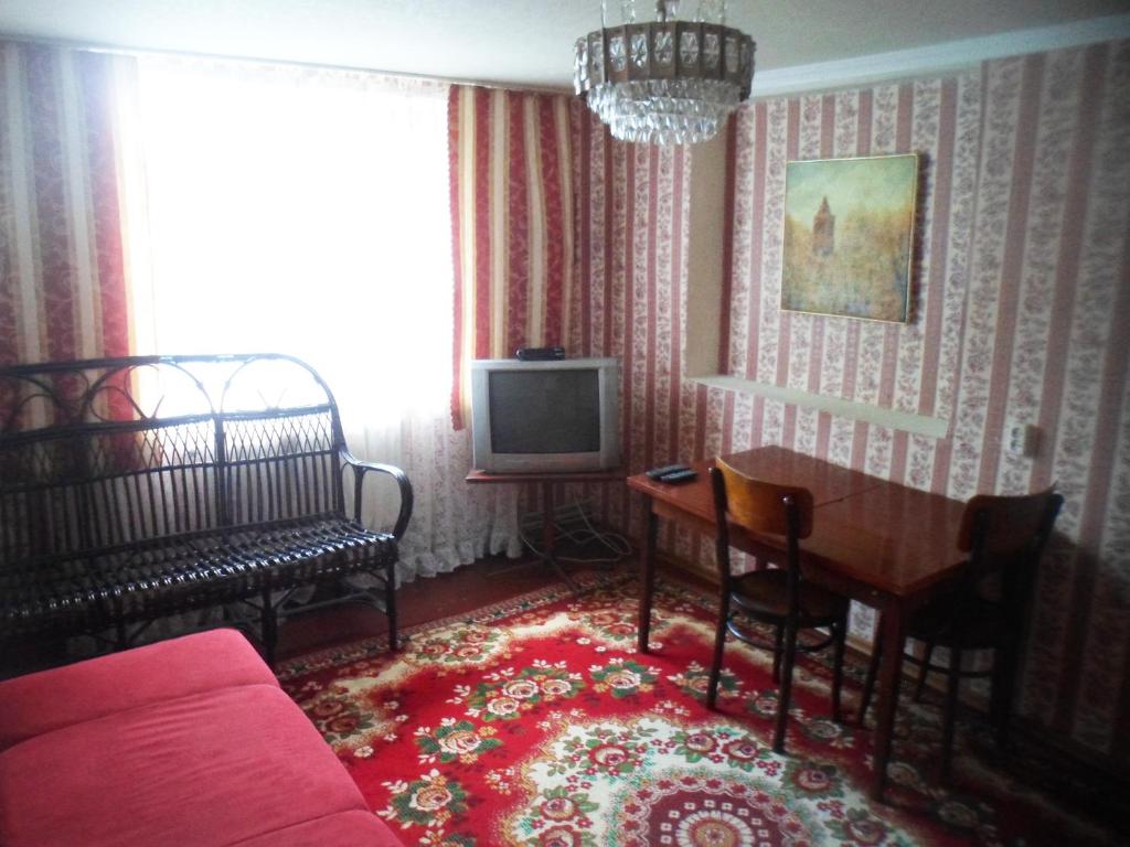 uma sala de estar com um sofá, uma mesa e uma televisão em Дом em Okhtyrka