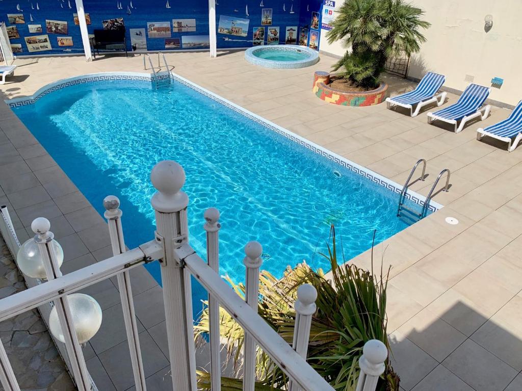 una piscina con sedie blu e recinzione di Amerique Hotel Palavas - Piscine & Parking - Plage a Palavas-les-Flots
