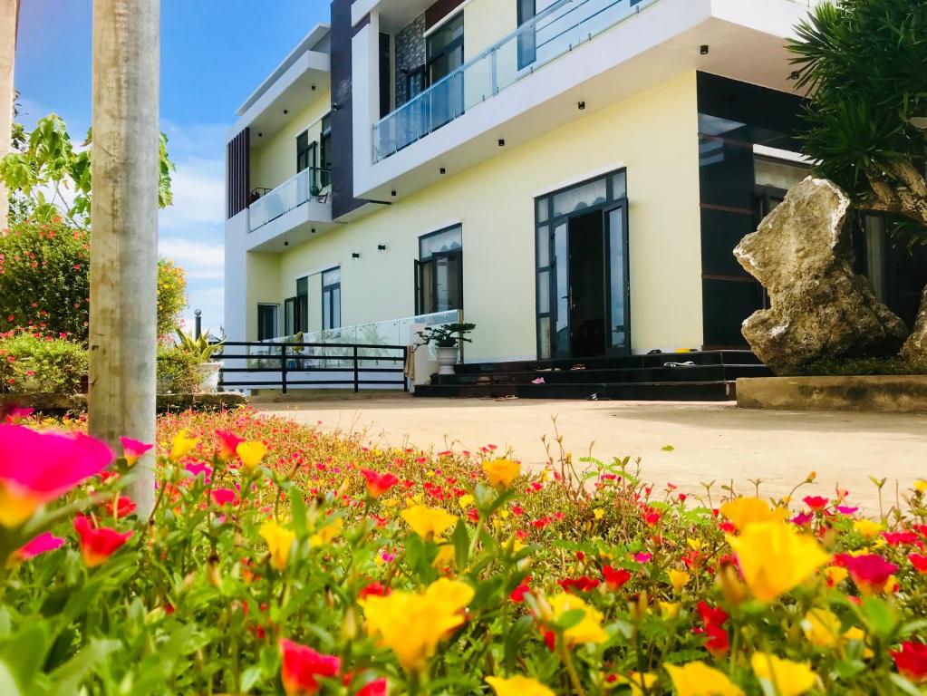 un bâtiment avec des fleurs devant lui dans l'établissement Quang Vinh - Đảo Lý Sơn, à Ly Son